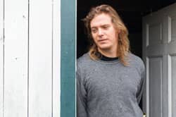 Man leaning in doorway of 30-day rehab