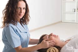 Therapist massages patient's head lying on table