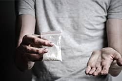 Closeup of man holding cocaine bag and gesturing towards it