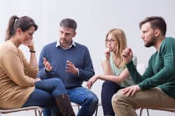 group of people in chairs holding intervention for friend with addiction