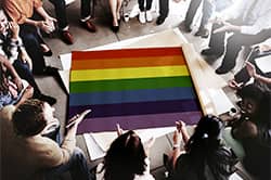 Group of LGBT people in treatment sitting around a rainbow flag