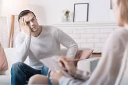 Stressed man talks with his therapist in rehab
